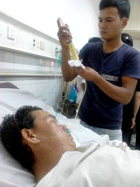 Không tiền đóng viện phí, con không dám nhận cha - 2 Nhờ mọi người giúp đỡ, em Tâm mua được suất cháo của bệnh viện và đang bơm vào dạ dày cho cha.