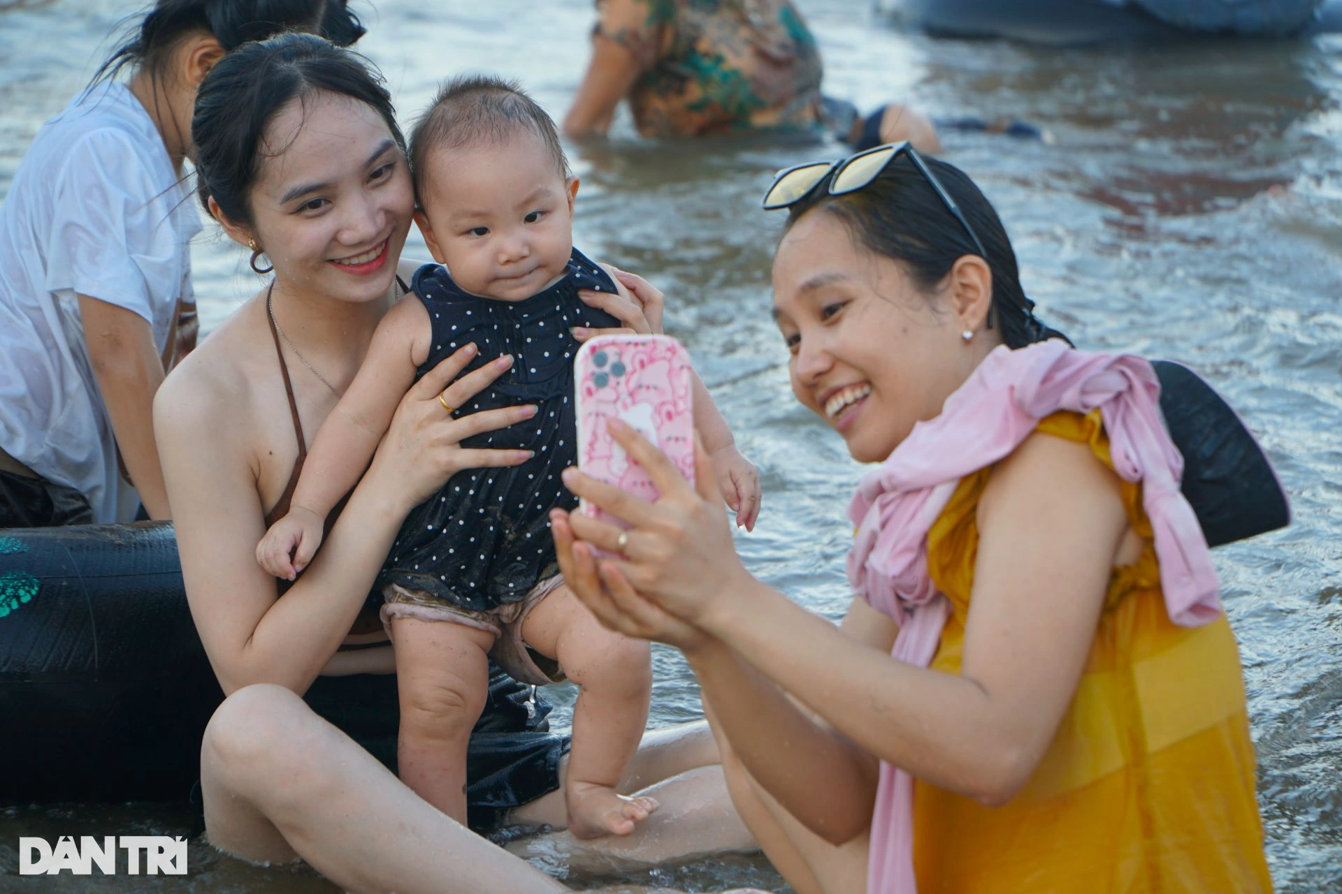 Một em nhỏ được mẹ cho xuống biển tắm mát trong ngày hè nóng bức.