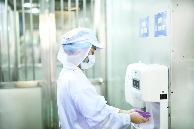 Thâm nhập nhà máy sản xuất mì ăn liền cao cấp hàng đầu tại Việt Nam - 2 Công nhân phải mặc trang phục bảo hộ lao động, rửa sạch tay, xịt cồn và đeo găng tay trước khi bước vào xưởng.