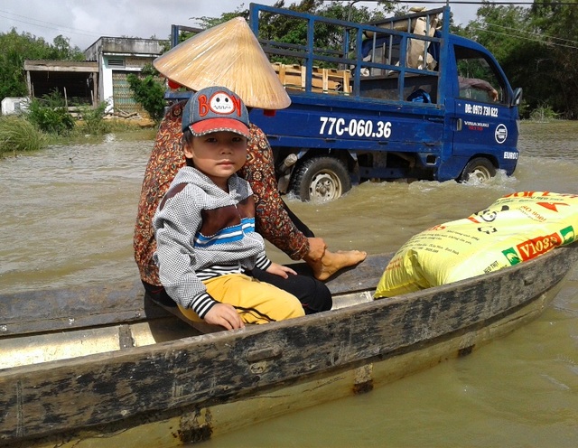 Mưa lớn cộng thủy điện xả lũ, nhiều nơi ngập sâu - 13 Một em nhỏ theo mẹ đi chợ trong nước lũ