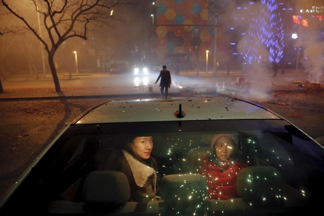 Trung Quốc: Một bé gái và một phụ nữ ngồi bên trong xe ô tô khi pháo hoa được bắn lên bầu trời mừng năm mới ở thủ đô Bắc Kinh, Trung Quốc ngày 7/2.