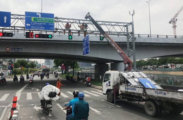 Lắp thêm biển chỉ đường bằng tiếng Anh trên đại lộ Sài Gòn - 3 Các công nhân đang thi công thay thế, lắp bổ sung biển chỉ đường bằng tiếng Anh tại giao lộ Võ Văn Kiệt - Nguyễn Thái Học, sáng 20/5.