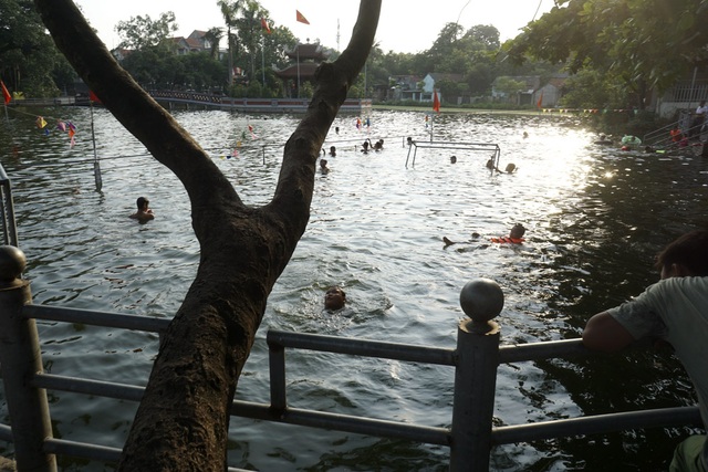 Dân làng "chế" ao thành bể bơi cho trẻ nhỏ - 1
Ao làng Thiên nằm bên cạnh chùa Hương Trai thuộc thôn Thống Nhất, xã Dương Liễu (Hoài Đức,Hà Nội). Ao rộng khoảng 7.000 m2, ở giữa có một đảo nhỏ được xây thành Nhà tưởng niệm Bác Hồ. Ao có từ lâu đời, trước đây là 3 ao nhỏ nằm sát nhau, thời bao cấp chia cho các xã viên thả cá, thả bèo, rau... tuy vậy người dân vẫn xuống đây bơi lội trong những ngày hè nóng nực.