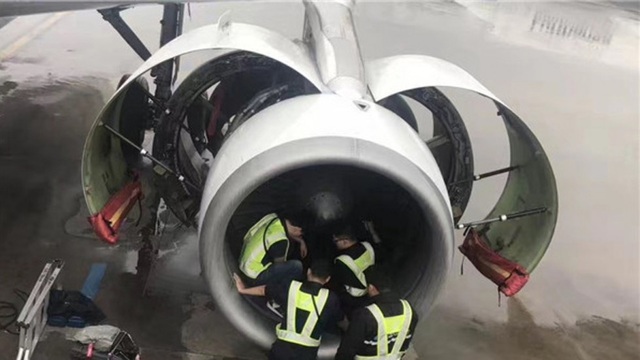 Các nhân viên bảo trì kiểm tra động cơ máy bay sau khi hành khách ném xu vào cầu may. (Ảnh: SCMP)