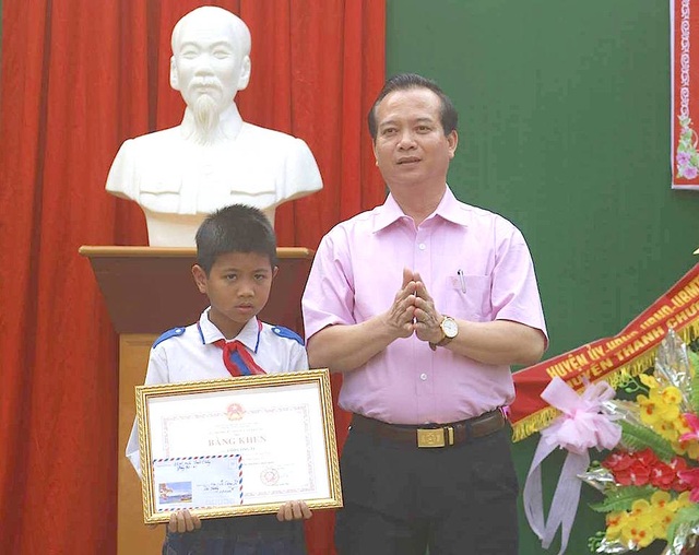 Trao Huân chương của Chủ tịch nước đến học sinh lớp 5 cứu hai em nhỏ khỏi đuối nước - 2 Ông Nguyễn Văn Quế - Chủ tịch UBND huyện Thanh Chương trao Bằng khen của Bộ GD&ĐT cho em Tú.