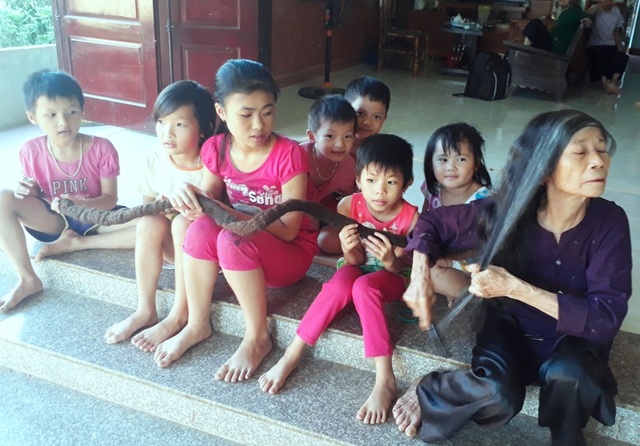 Kỳ lạ cụ bà sở hữu “bộ tóc rồng” dài gần 3m - 2 Các cháu nhỏ vui đùa bên mái tóc kỳ lạ của cụ Nghiên