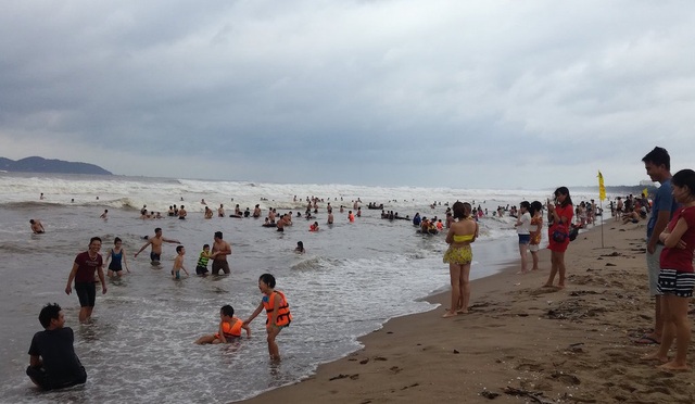Trẻ em người lớn hồn nhiên tắm biển dù thời tiết đang rất xấu.
