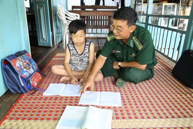 Bộ đội biên phòng Đồng Tháp “nâng bước” học sinh nghèo vùng biên - 1 Thiếu tá Đặng Văn Trí, Đội phó vận động quần chúng, Đồn Biên phòng Bình Thạnh, hướng dẫn em Nguyễn Văn Thiện làm bài tập