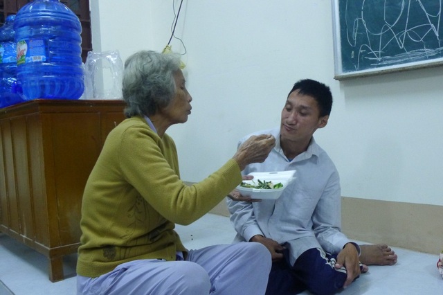 Cận cảnh cuộc sống của người dân tại nơi tạm trú tránh bão - 6
Bà Mum bón cơm cho cháu ngoại 26 tuổi bị tật nguyền từ nhỏ