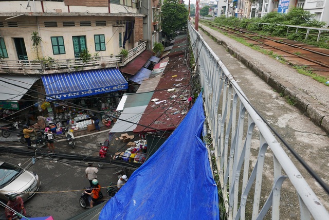 
Góc nhìn cho thấy dãy ki-ốt áp sát gầm cầu đường sắt, đối diện là nhà cửa khu phố cổ Hà Nội.
