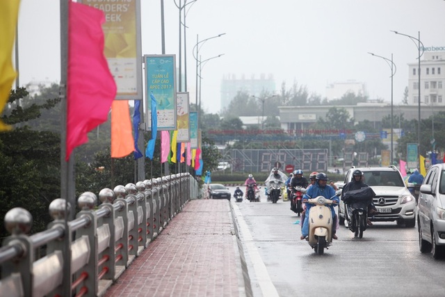 Đà Nẵng trong cơn ảnh hưởng bão số 12 trước thềm APEC - 2
Người dân đi qua cầu sông Hàn dưới trời mưa tầm tã, bên cạnh các pano, băng rôn APEC treo trên các cột đèn.