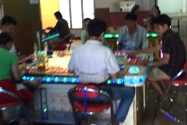 Thâm nhập sòng bạc khủng núp bóng tiệm game bắn cá - 2 Nhóm người vây quanh một máy bắn cá với vẻ mặt bơ phờ, mệt mỏi vì săn nàng tiên cá thâu đêm.