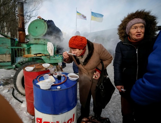 Chiến sự "đốt nóng" miền đông Ukraine - 17
Một phụ nữ đứng ăn giữa trời lạnh trung tâm tạm trú. (Ảnh: Reuters)