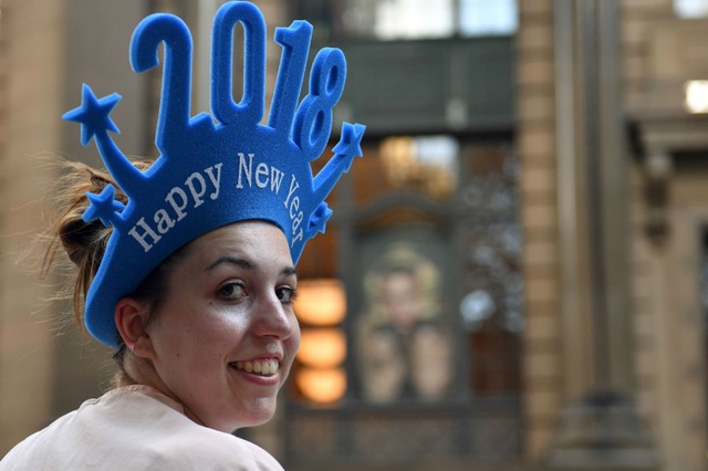 Không khí đón năm mới 2018 rộn ràng khắp thế giới - 7 Một phụ nữ đội mũ có dòng chữ “Chúc mừng năm mới 2018” tại thành phố Sydney, Australia để chuẩn bị chào đón năm mới. (Ảnh: AFP)