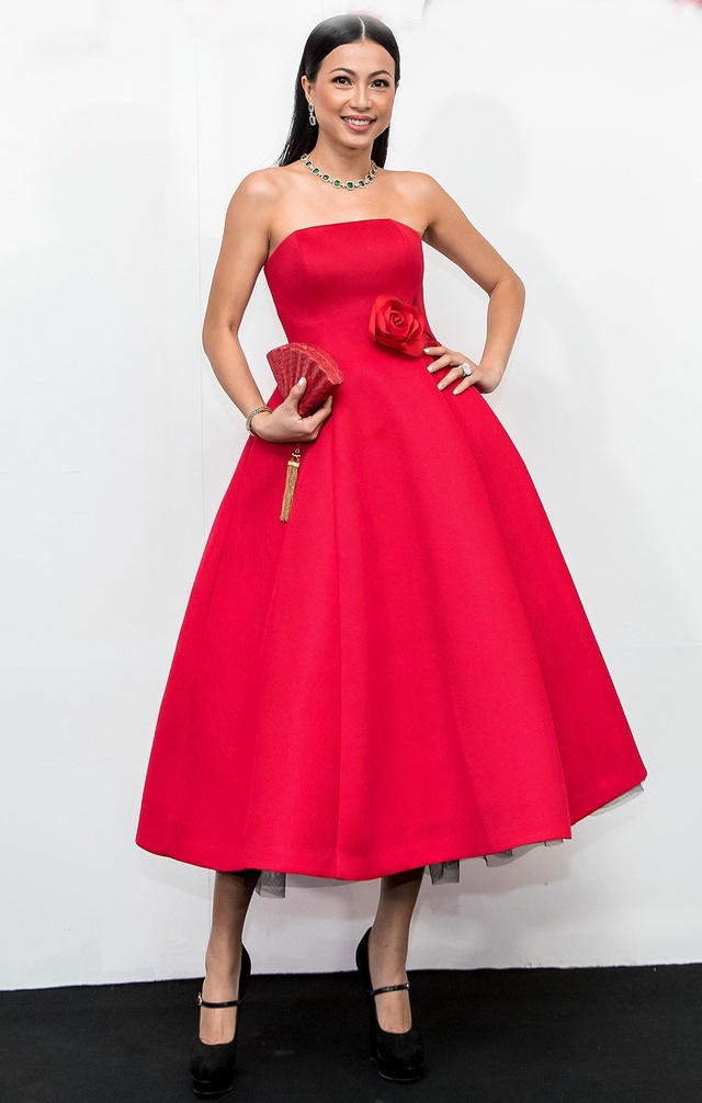 Hoa hậu Ngô Mỹ Uyên diện đầm xòe cúp ngực với điểm nhấn là hoa hồng ở thắt eo. Người đẹp phối trang phục cùng clutch cầm tay độc đáo, trang sức màu xanh nổi bật.