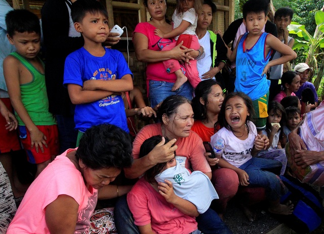 Philippines phá âm mưu tấn công thành phố 300.000 dân - 2 Người dân ở Pigcawayan ngồi chờ xe tới để đưa đi sơ tán sau cuộc tấn công của phiến quân (Ảnh: Reuters)