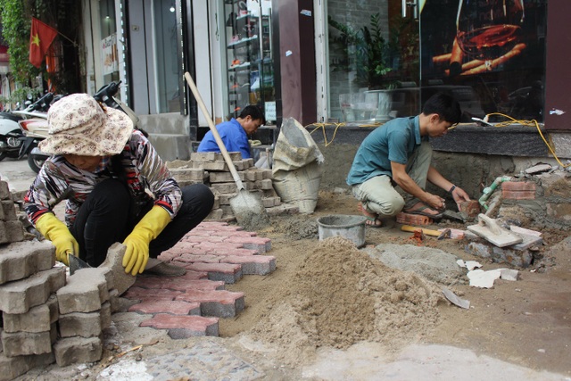Thợ hồ kiếm tiền triệu/ngày nhờ sửa bậc tam cấp - 1 Một nhóm thợ đang sửa lại bậc tam cấp cho một cửa hàng trên đường Xã Đàn.