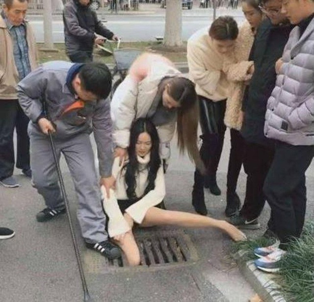 Gái xinh vừa đi vừa bấm điện thoại sụt chân xuống nắp cống kẹt cứng - 2 Nhiều người đã vây quanh trấn an cô gái