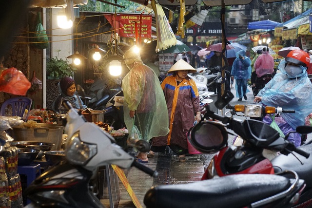 
Các bà nội trợ trùm kín áo mưa đi chợ với lỉnh kỉnh các loại túi đựng thực phẩm, rất bất tiện.
