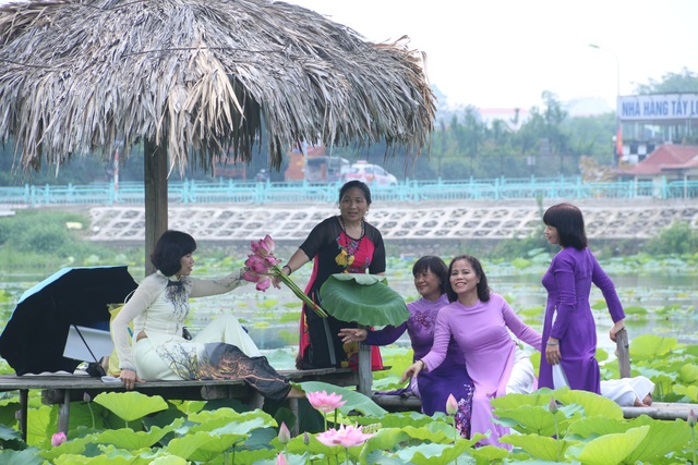 Hà Nội: Lội bùn chụp ảnh sen, phó nháy kiếm tiền triệu mỗi ngày - 5 Không chỉ có các bạn trẻ thích chụp ảnh cùng hoa sen, nhiều phụ nữ trung tuổi cũng ra hồ tạo dáng với hoa sen bên áo dài truyền thống để ghi lại những kỷ niệm.
