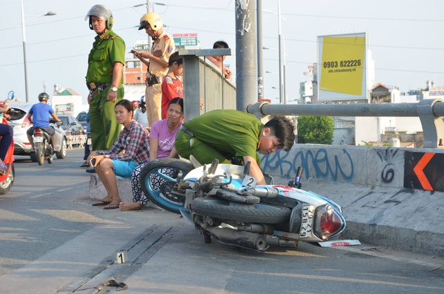 Đâm xe vào thành cầu, 2 thanh niên rơi xuống sông - 1 Công an khám nghiệm hiện trường chiếc xe máy còn lại trên cầu