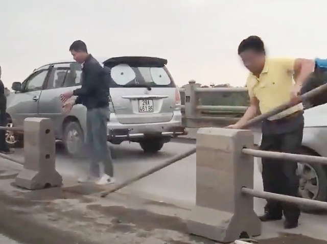 Tài xế ô tô tự tháo dải phân cách trên cầu Thanh Trì để... "nhảy" làn - 1 Hình ảnh một số người đàn ông tháo dải phân cách trên cầu Thanh Trì. (Ảnh cắt từ clip).