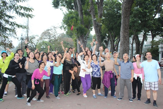 Muôn kiểu tập thể dục của người Hà Nội - 14 Cả lớp yoga cười chụp ảnh lưu niệm với du khách nước ngoài sau khi kết thúc buổi tập. Cô Kim Liên, một thành viên của lớp cho biết: Nhà cô ở Tôn Đức Thắng, nhưng ngày nào cũng bắt xe bus đến Hồ Gươm để kịp bắt đầu tập yoga lúc 6 giờ. Nhờ có yoga cười giúp cô vừa vui vẻ, hứng khởi cho cả ngày, lại vừa chẳng bao giờ ốm đau.