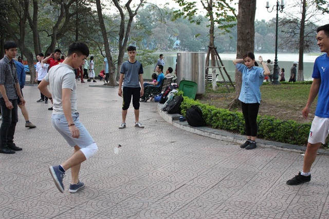 Muôn kiểu tập thể dục của người Hà Nội - 4 Từ khoảng 4 giờ chiều, ở góc hồ Gươm, đối diện Tràng Tiền Plaza, các bạn trẻ cùng nhau tụ tập và chơi đá cầu. Có khoảng hơn 20 người chia thành các nhóm nhỏ. Những vị khách hiếu kỳ cũng có thể tham gia hoạt đông thú vị này.