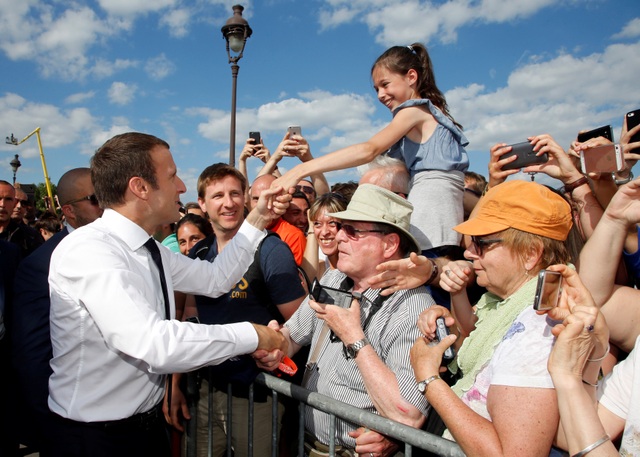 Tổng thống Pháp “lăn xả” trong trận đấu quần vợt trên xe lăn - 1 Tổng thống Macron bắt tay người dân khi tới khu vực tổ chức ngày hội Olympic tại Paris hôm 24/6 (Ảnh: Reuters)