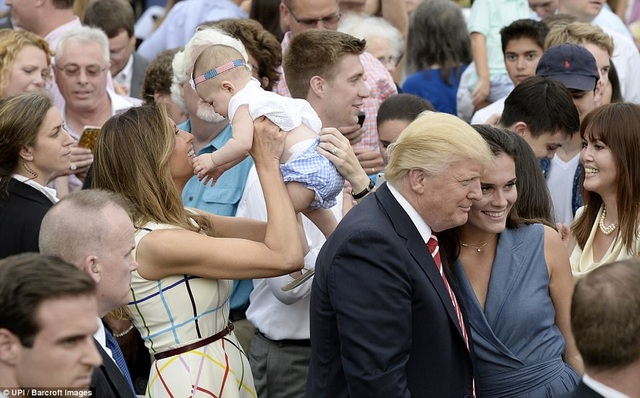 Đệ nhất phu nhân Mỹ bế một em nhỏ khi tham dự bữa tiệc ngoài trời hôm 22/6. Trước đó, bà Melania và con trai Barron Trump đã chuyển tới Nhà Trắng ở cùng Tổng thống Trump trước khi Barron bắt đầu năm học mới. (Ảnh: UPI)