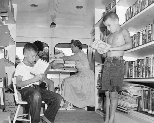 Hai cậu bé đang đọc “ngấu nghiến” những cuốn sách yêu thích bên trong một thư viện lưu động. Ảnh chụp hồi thập niên 1920.