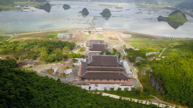 Toàn cảnh ngôi chùa rộng lớn nơi sẽ diễn ra đại lễ Phật đản Vesak 2019 - 8
Sự tích “Tiền lục nhạc - Hậu thất tinh” bắt nguồn từ đó. Tiền lục nhạc nghĩa là mặt trước có 6 quả núi giữa lòng hồ được ví là 6 quả chuông của nhà trời. Hậu thất tinh có nghĩa là phía sau có 7 ngọn núi có thể phát sáng khi có ánh trăng về ban đêm. Ngày nay, vào những đêm trăng rằm, ánh sáng lung linh từ trên đỉnh núi rọi xuống làm bừng sáng cả một vùng trời Tam Chúc rộng lớn.