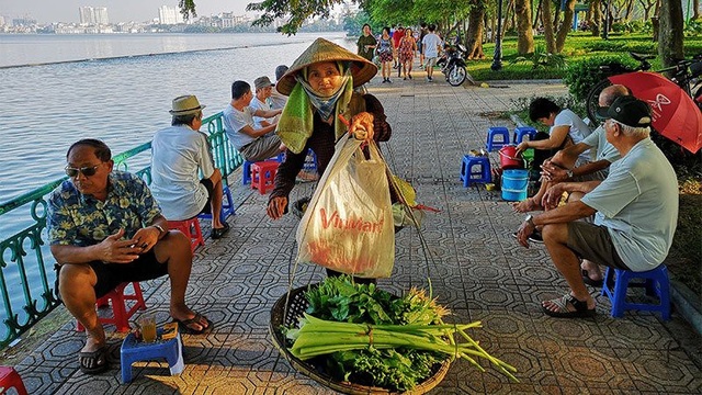 Hình ảnh Hà Nội hài hước, lạ lẫm không dành cho người dậy muộn - 13 Một phụ nữ gánh hàng rau đi qua những người đàn ông đang trầm tư bên chén chè sớm ven Hồ Tây.