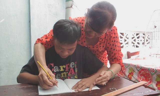 Cô giáo gần 20 năm dạy chữ miễn phí cho trẻ mồ côi, khuyết tật - 3 Cô Nga đang rèn chữ viết cho một học sinh của lớp