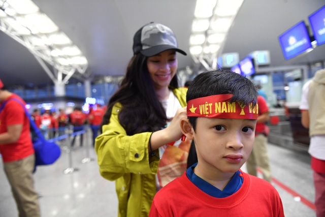 Cổ động viên Việt dậy từ sáng sớm, đáp chuyên cơ sang Malaysia cổ vũ đội nhà - 3 Trong đoàn người đi cổ vũ đội tuyển Việt Nam có cả những cổ động viên nhí. Trong ảnh là em Minh Anh (8 tuổi, Hà Nội) đang được người thân đeo băng rôn tiếp lửa cho đội nhà trước khi sang Malaysia.