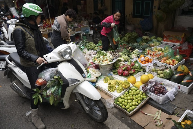 Phiên cuối năm tại "chợ nức tiếng" giữa lòng phố cổ Hà Nội - 9 Một phụ nữ với lỉnh kỉnh đủ loại rau quả trên chiếc xe máy của mình.