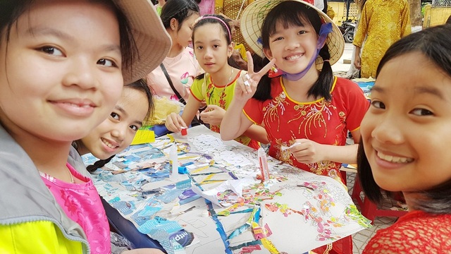Học sinh cấp 1 thích thú trong phiên chợ quê cố đô Huế - 3 Nữ học sinh xếp tranh giấy tươi cười chụp ảnh