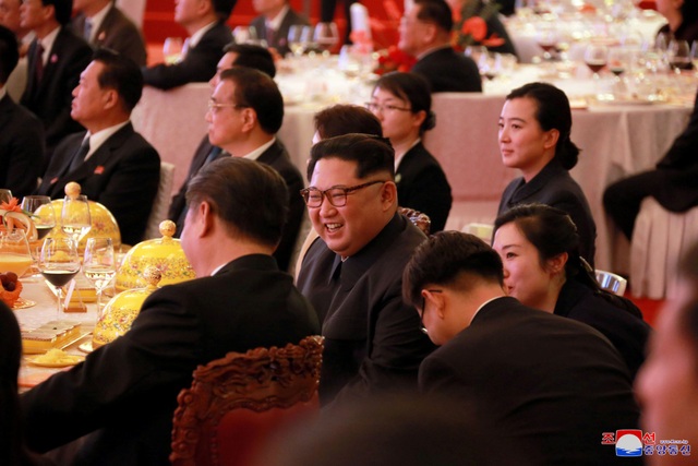 Hai nhà lãnh đạo Trung - Triều ngồi cạnh nhau trên bàn tiệc. Cả hai cùng theo dõi chương trình nghệ thuật chung.