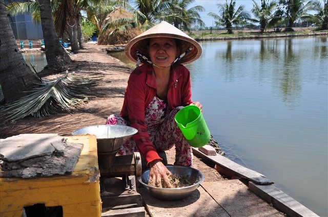 Làm giàu giữa mùa thiên tai - 2 Bà Chanh bên chiếc máy làm thức ăn cho tôm.