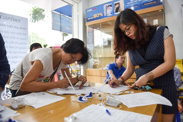 Hà Nội: Người dân mệt mỏi đi bổ sung thông tin cá nhân cho thuê bao - 4 Nhiều người không còn chỗ ngồi đành vừa đứng vừa ghi thông tin vào phiếu cập nhật thông tin.