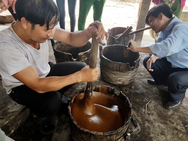 Giữ lửa cho lò đường thủ công cuối cùng - 7 Sau khi nhúng bánh tráng xong, nước đường còn lại được đổ vào thùng gỗ đảo liên tục để đường nguội rồi chắt vào bát