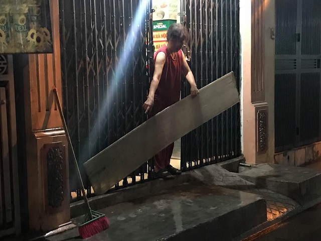 Phố phường Hà Nội bì bõm sau cơn mưa chiều cuối tuần - 17 Nhiều người dân dùng cả tấm chắn để ngăn không cho nước vào nhà sau cơn mưa rào gây ngập úng.