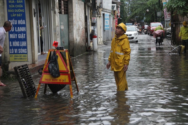 Phố phường Hà Nội bì bõm sau cơn mưa chiều cuối tuần - 3 Công nhân thoát nước có mặt để dựng biển báo cảnh giới cho người dân đi qua khu vực đang thoát nước.