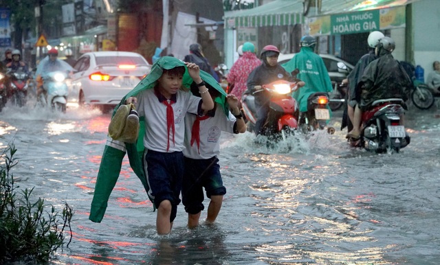Sài Gòn mưa to, học sinh bì bõm lội nước về nhà - 13 2 học sinh tiểu học che áo mưa dìu nhau qua dòng nước