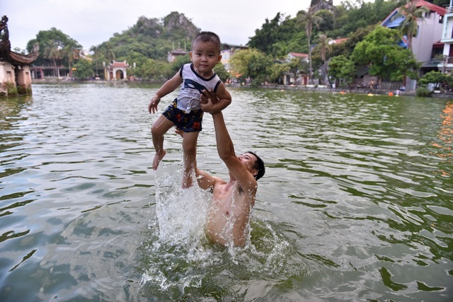 Trẻ em tắm giải nhiệt ở hồ nghìn tuổi ngoại thành Hà Nội - 12
Một em nhỏ được bố đưa xuống hồ đùa nghịch với nước.