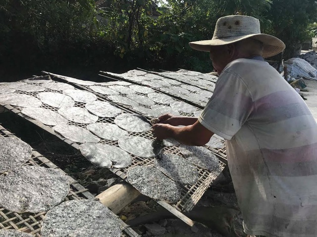 Làng nghề bánh đa ở xứ Nghệ vẫn luôn đỏ lửa giữa trời nắng 40 độ C - 3 Dưới nắng nóng hơn 40 độ C, bà con vẫn luôn tay trở đều từng chiếc bánh để bánh được khô đều, không bị cong vênh. Ảnh: Mỹ Hà