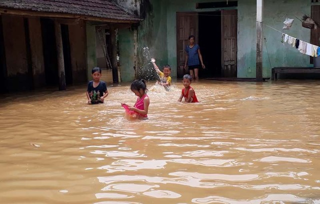 Dân "ôm" tài sản, lợn gà chạy lên đê tránh lũ - 4 Mặc dù nước lũ còn ngập sâu, nhưng nhiều đứa trẻ vẫn vô tư tắm nước, đùa nghịch ngay trong sân nhà. Đến thời điểm hiện tại, nước sông Bưởi đang xuống với mức độ chậm khiến hàng trăm ngôi nhà của các hộ dân sống dọc 2 bên bờ sông Bưởi vẫn ngập sâu trong nước.