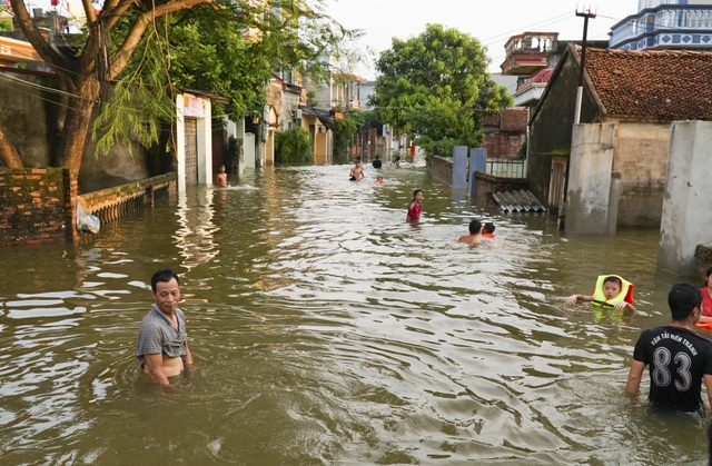 Hà Nội: Xã ngoại thành hễ mưa là ngập, dân chèo thuyền trên đường làng - 2
Người dân tại các thôn Cấn Thượng, Định Tú, Bến Vôi... của xã Cấn Hữu, Tuyết Nghĩa bị ngập sâu hơn 1m nước, bị cô lập hoàn toàn, cuộc sống đảo lộn. Nhiều trẻ em trong vùng tổ chức thi bơi lội ngay trên đường làng nay ngập sâu trong nước.