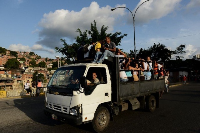 “Xe nhồi nhét người” ngày càng thịnh hành ở Venezuela - 1 Người dân Venezuela đi trên một chiếc xe lồng trong khu ổ chuột Caracas. (Nguồn: AFP Photo/Federico PARRA)