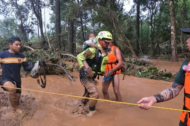 Lời cảnh báo trên mẩu giấy trước giờ vỡ đập tại Lào - 1
Đội cứu hộ Thái Lan cõng một em nhỏ qua sông tại tỉnh Attapeu (Ảnh: AFP)